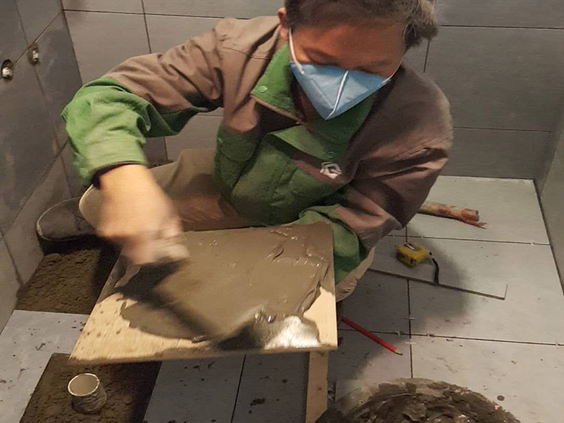 廁所貼地磚：
1、基層處理：把沾在基層上的浮漿、落地灰等用暫子或鋼絲刷清理掉，再用掃帚將浮土清掃干凈。
2、找標(biāo)高：根據(jù)水平標(biāo)準(zhǔn)線和設(shè)計(jì)厚度，在四周墻、柱上彈出面層的上平標(biāo)高控制線。
3、排磚：將房間依照磚的尺寸留縫大小，排出磚的放置位置，并在基層地面彈出十字控制線和分格線。
4、鋪設(shè)結(jié)合層砂漿：鋪設(shè)前應(yīng)將基底濕潤(rùn)，并在基底上刷一道素水泥漿或界面結(jié)合劑，隨刷隨鋪設(shè)攪拌均勻的干硬性水泥砂漿。
5、鋪磚：將磚放置在于拌料上，用橡皮錘找平，之后將磚拿起，在干拌料上澆適量素水泥漿，同時(shí)在磚背面涂厚度約lnm的素水泥膏，再將磚放置在找過平的干拌料上，用橡皮錘按標(biāo)高控制線和方正控制線坐平坐正。
6、鋪磚時(shí)應(yīng)先在房間中間按照十字線鋪設(shè)十字控制磚，之后按照十字控制磚向四周鋪設(shè)，并隨時(shí)用2m靠尺和水平尺檢查平整度。大面積鋪貼時(shí)應(yīng)分段、分部位鋪貼。
7、養(yǎng)護(hù)：當(dāng)磚面層鋪貼完24h內(nèi)應(yīng)開始澆水養(yǎng)護(hù)，養(yǎng)護(hù)時(shí)間不得小于7d。